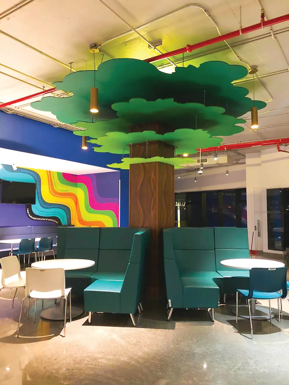 Área de descanso con árbol decorativo y mural de colores